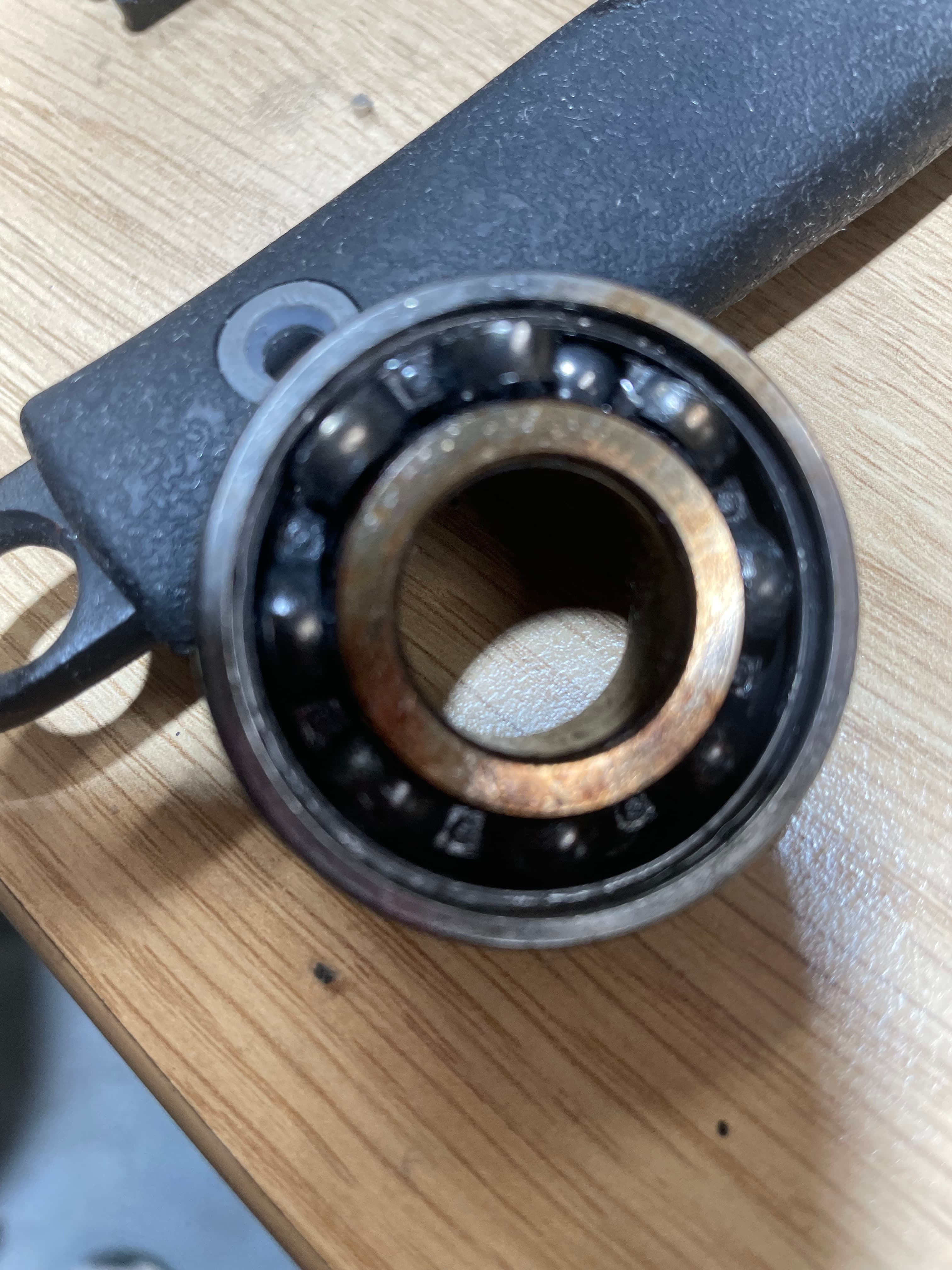 Worn ball bearing with rust on the inner race — removed from machine and placed on workbench for inspection